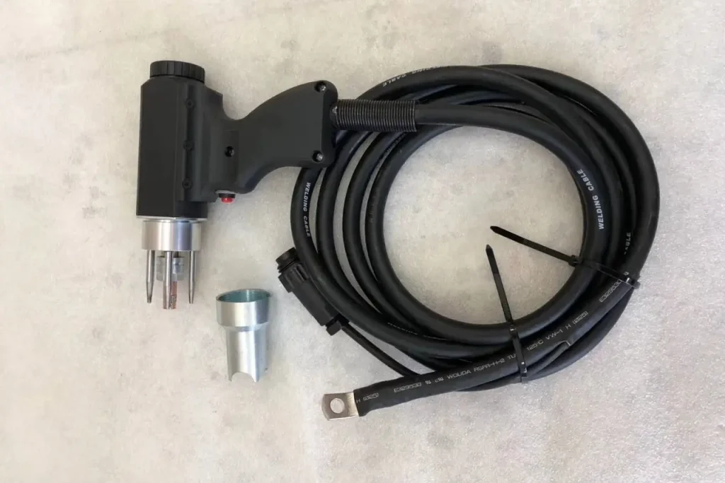A specialized black stud welding gun with an interchangeable silver nozzle and grounded heavy-duty welding cable.