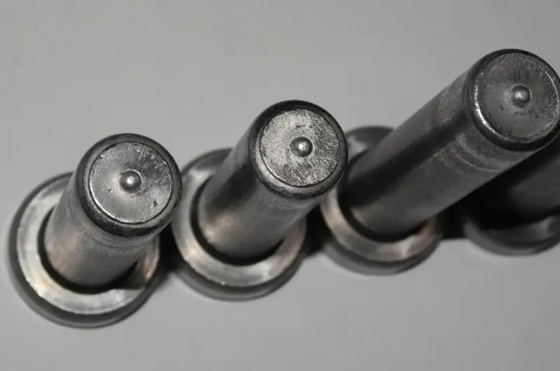Close-up view of multiple shear studs showing integrated aluminum flux balls at the welding tips for consistent arc ignition.