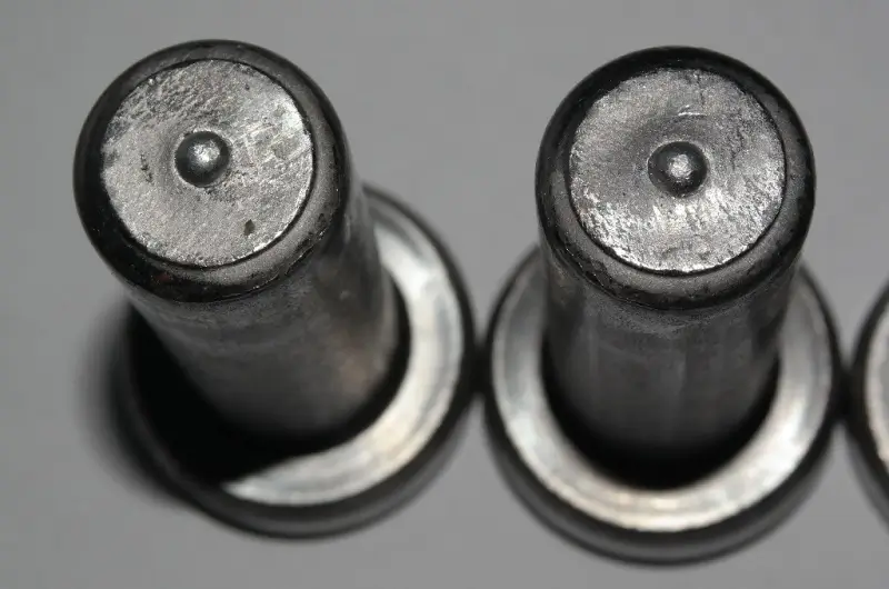 High-definition close-up of the ignition tip of two steel shear studs featuring pre-installed aluminum flux balls for arc stabilization.