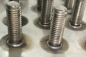Close-up of short cycle drawn arc stud welding on steel plate, demonstrating the uniform, high-strength weld collar achieved by this fast structural connection method.