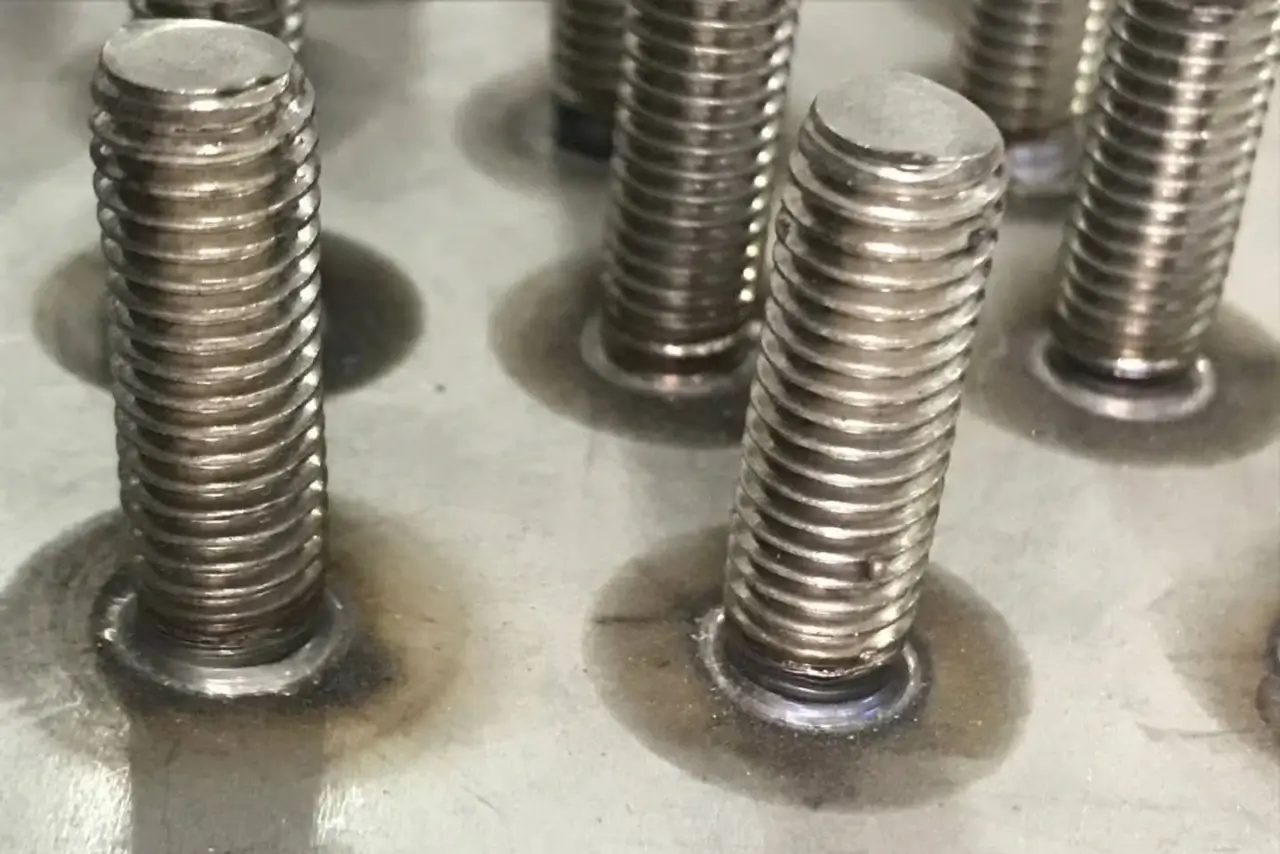 Close-up of short cycle drawn arc stud welding on steel plate, demonstrating the uniform, high-strength weld collar achieved by this fast structural connection method.