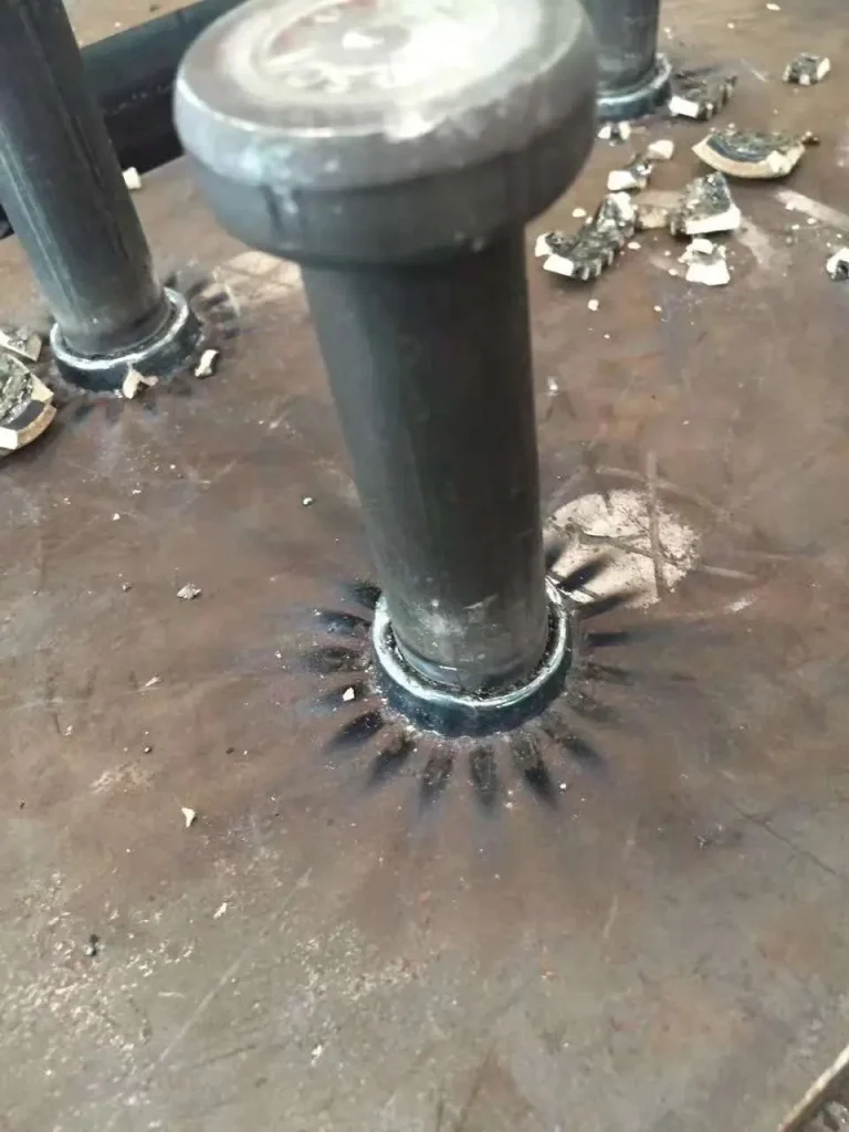 Shear stud welded to steel with remnants of the ceramic ferrule being chipped away.