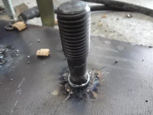 A fully threaded welding stud successfully joined to a metal plate.
