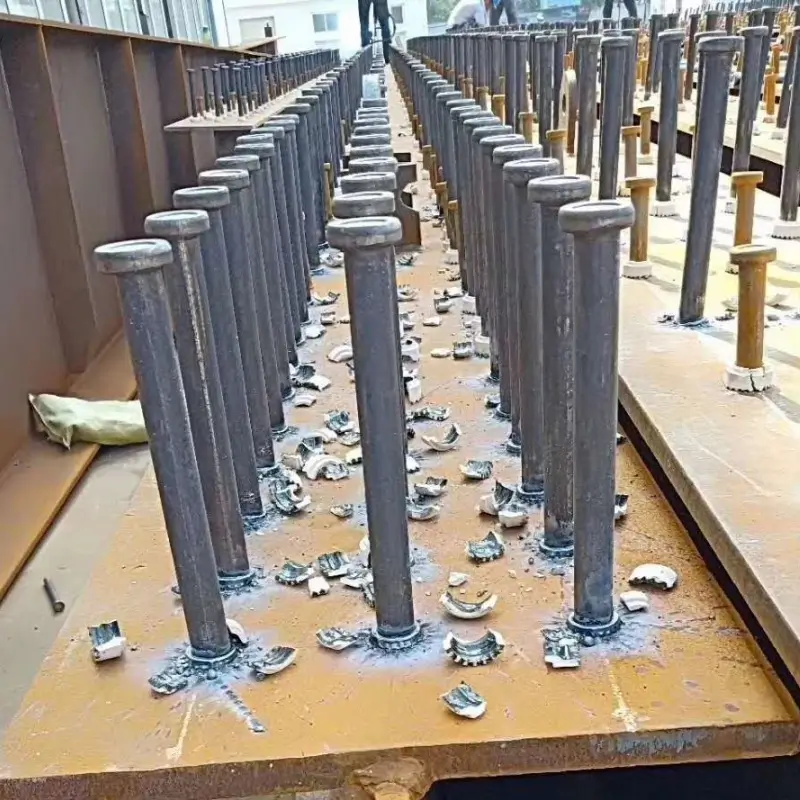 Close-up of high-quality welded shear studs on a steel plate with shattered ceramic ferrules after welding.